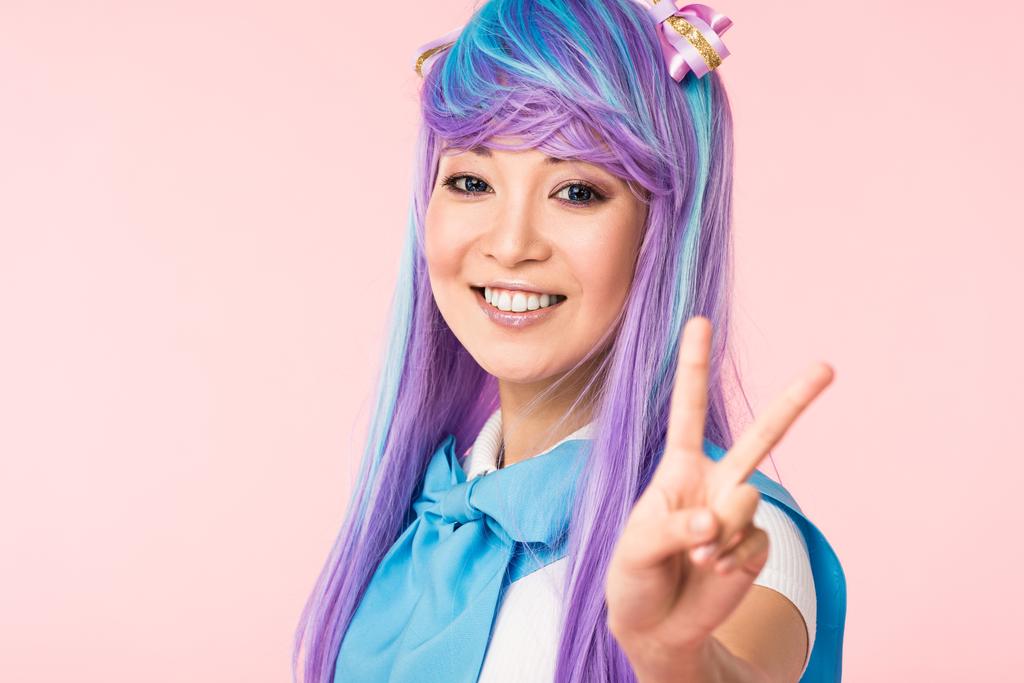 Blissful asiático anime chica en púrpura peluca mostrando paz signo aislado en rosa
 - Foto, imagen