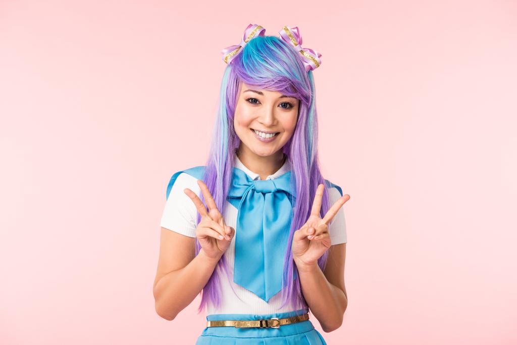 Χαρούμενος Ασιάτης/ισσα anime κορίτσι σε μωβ περούκα δείχνει ειρήνη σημάδια απομονωθεί σε ροζ - Φωτογραφία, εικόνα