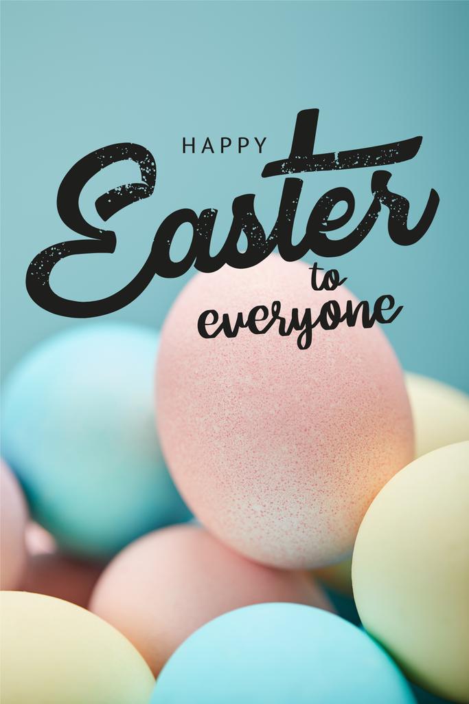 hromada barevných malovaných kuřecích vajíček s šťastným Velikonocemi pro všechny nápisy na modrém pozadí - Fotografie, Obrázek