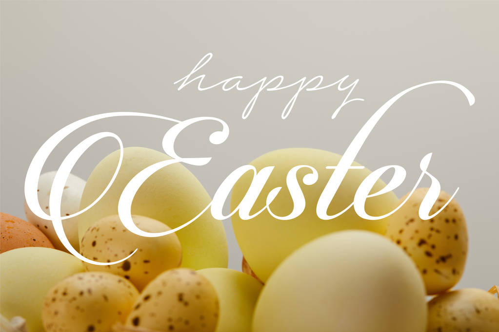 κίτρινο ζωγραφισμένο κοτόπουλο και ορτύκια αυγά με χαρούμενο Πάσχα γράμματα σε γκρίζο φόντο - Φωτογραφία, εικόνα