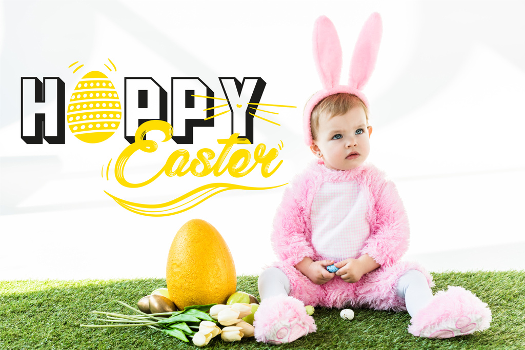 カラフルな鶏の卵、チューリップ、黄色のダチョウの卵の近くに座ってバニーの衣装でかわいい赤ちゃんと幸せなイースターのレタリング - 写真・画像