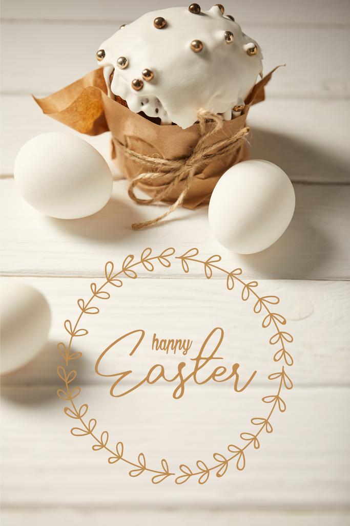 Traditioneller Osterkuchen und weiße Hühnereier auf weißem Holztisch mit fröhlichem Osteraufdruck - Foto, Bild