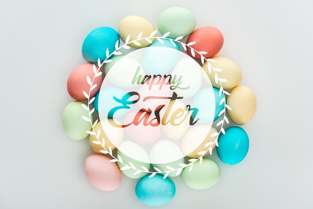 top view of painted multicolored eggs with happy Easter white lettering in circle - Photo, Image
