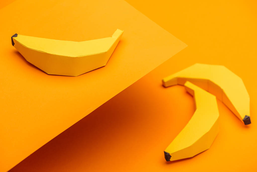 オレンジ色の紙に手作りの折り紙バナナを持つ背景  - 写真・画像