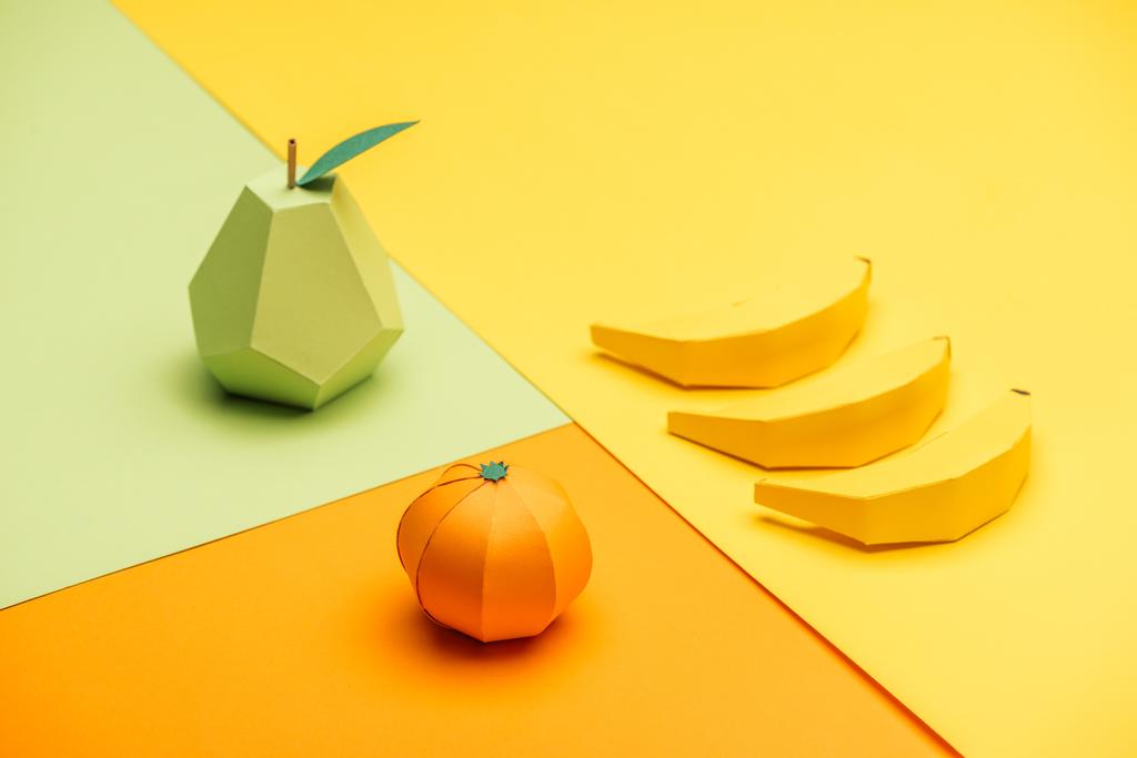 pera de origami hecha a mano, plátanos y mandarina sobre papel colorido
 - Foto, imagen