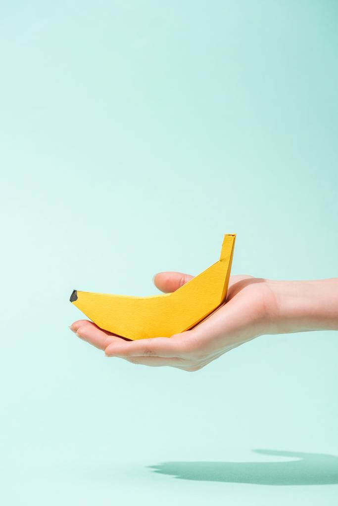 vista cortada de jovem segurando banana de papel em turquesa com espaço de cópia
 - Foto, Imagem