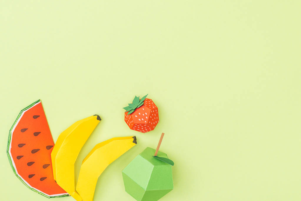 Draufsicht auf bunte Origami-Bananen, Apfel, Erdbeere und Wassermelone isoliert auf Grün mit Kopierraum - Foto, Bild