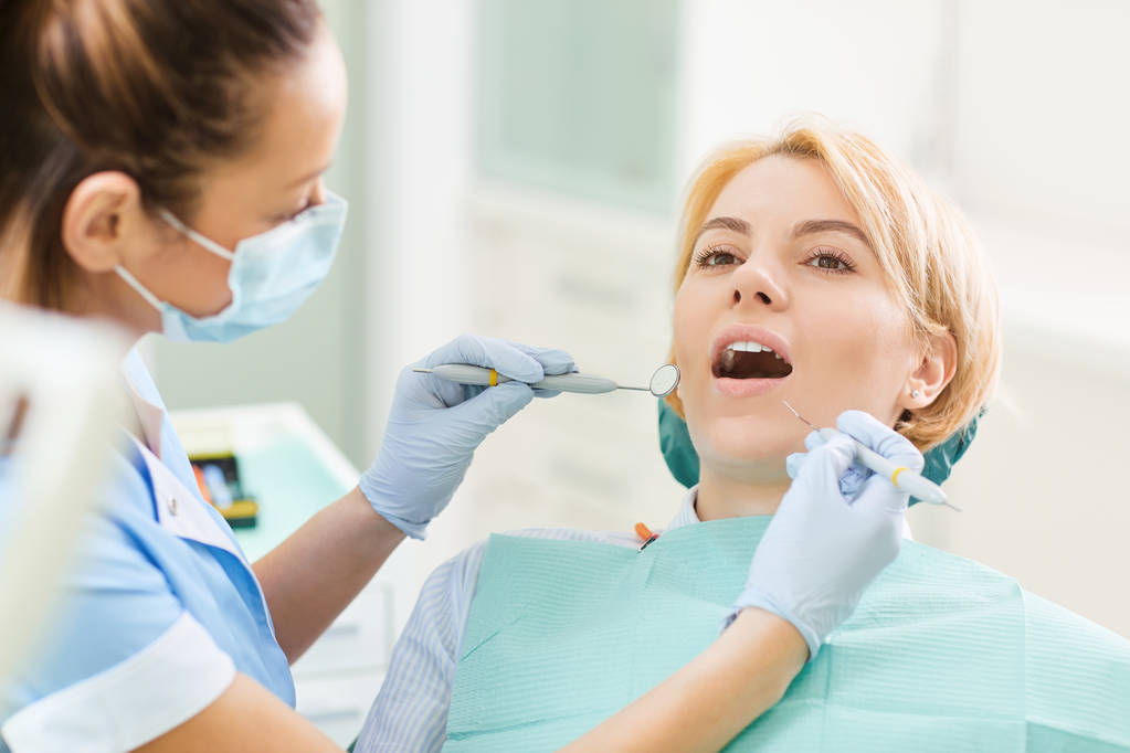 Mujer dentista comprueba los dientes de la chica
 - Foto, imagen