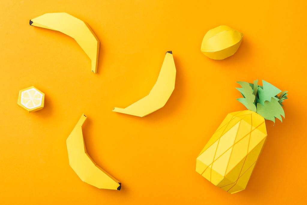 top view of handmade paper lemons, bananas and pineapple isolated on orange - Photo, Image