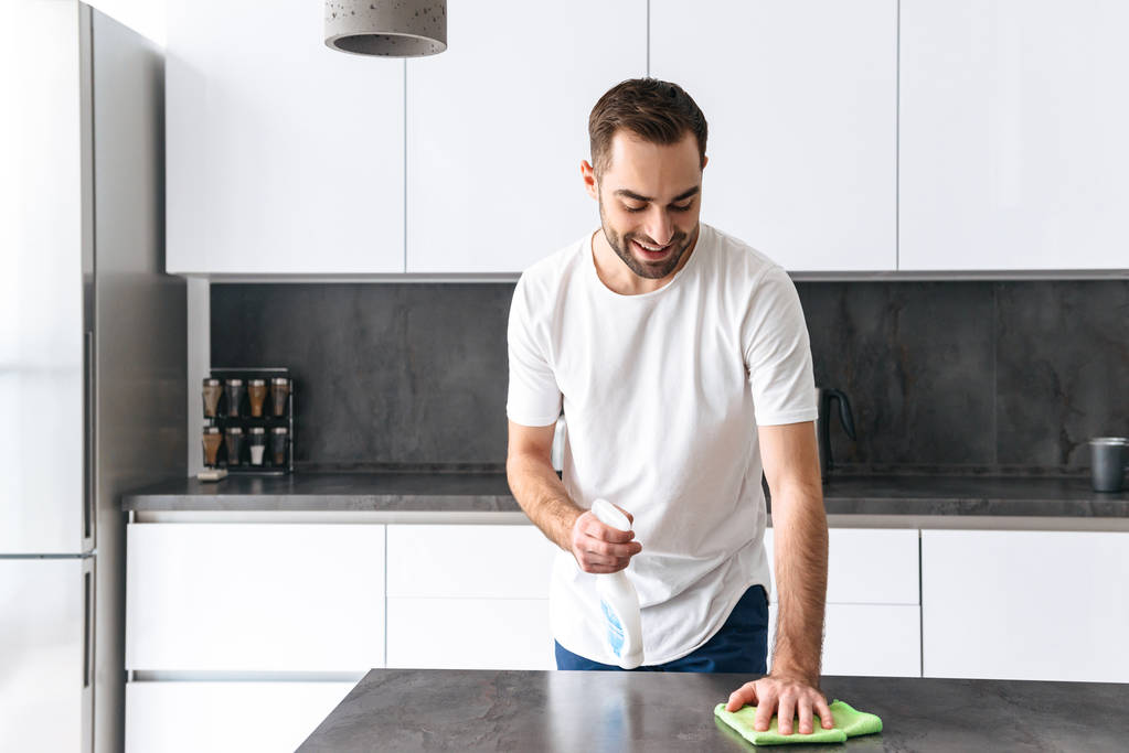Atrakcyjny młody człowiek sprzątanie kuchni - Zdjęcie, obraz