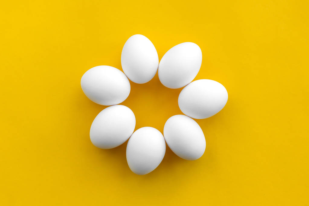 Bílé Kuřecí vejce leží ve formě květiny na žlutém pozadí. Zdravý organický potravinářský a dietní koncept. Abstrakce. Velikonoční téma - Fotografie, Obrázek