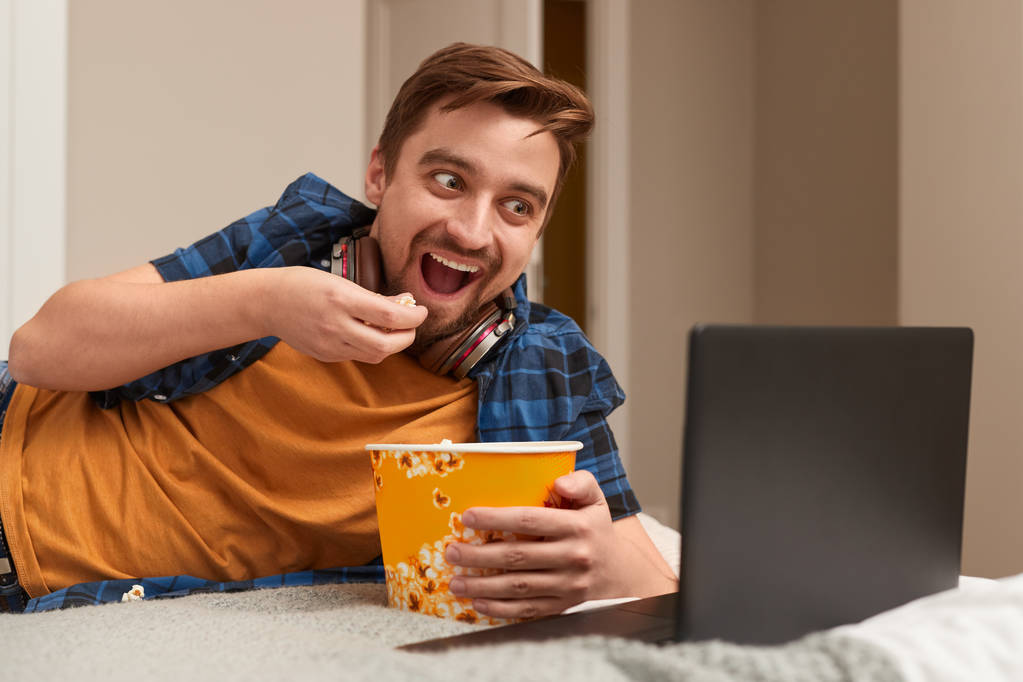 Захоплений чоловік їсть попкорн і дивиться фільм
 - Фото, зображення