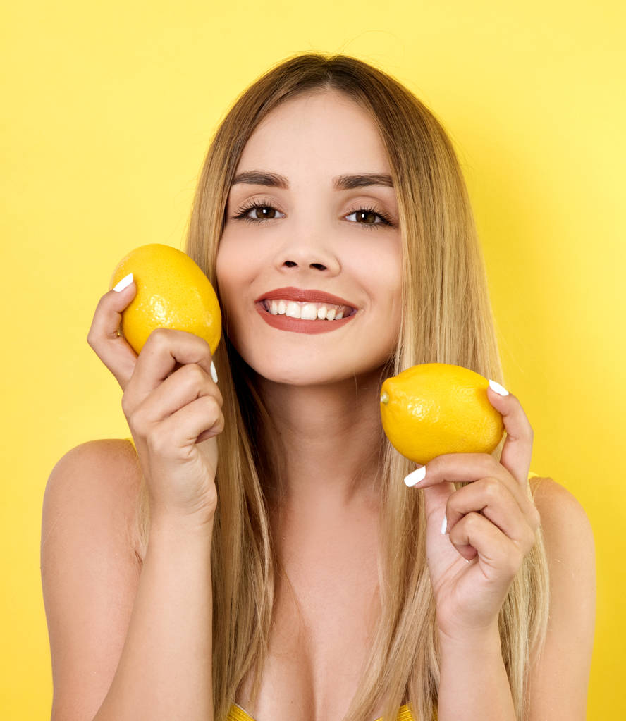 jonge vrouw poseren met citroenen - Foto, afbeelding