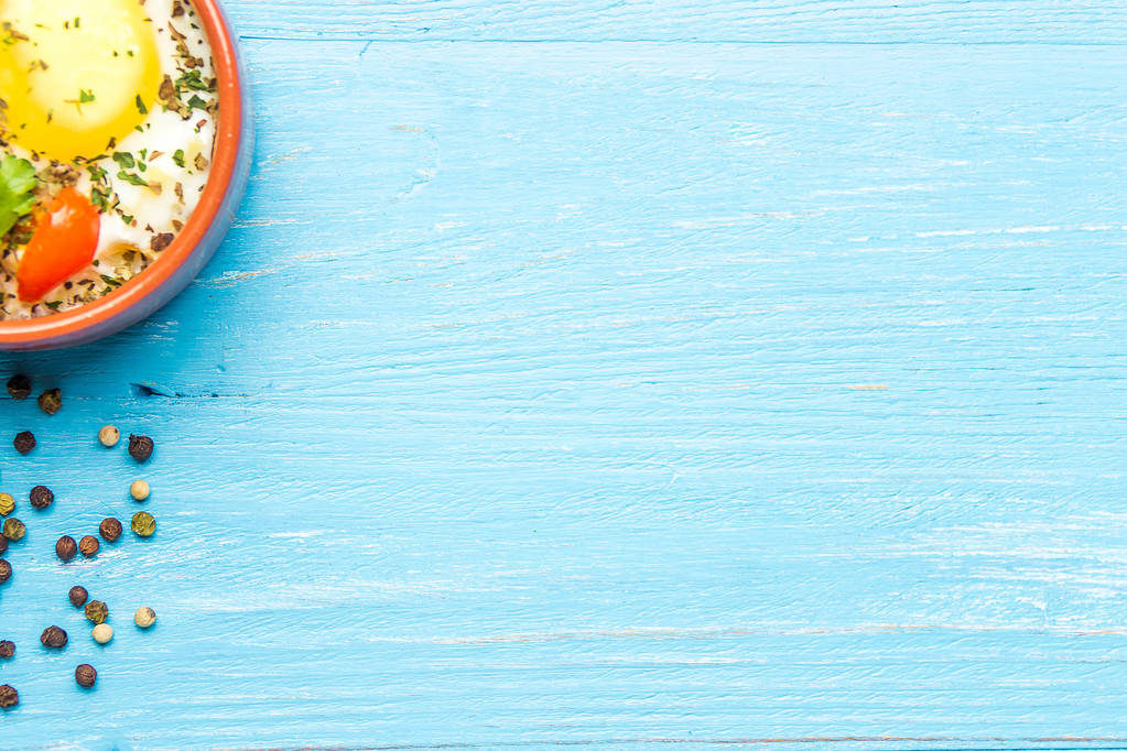 Nasavená vejce v keramických kokotte na modrém dřevěném stole, snídaně. Zobrazení nahoře, kopírování místa pro text. - Fotografie, Obrázek