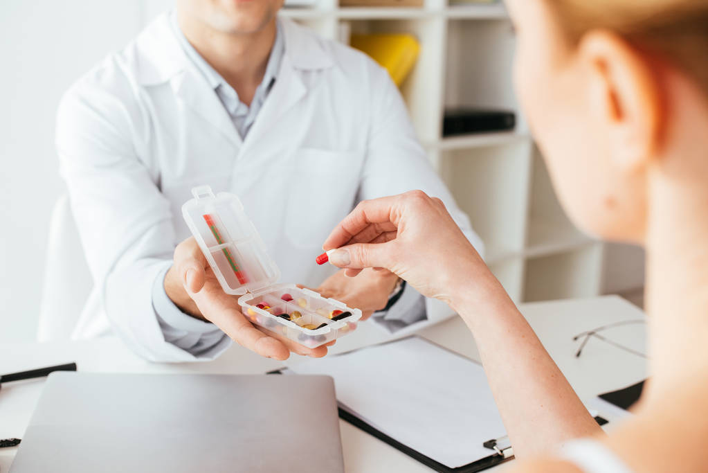 Ausgeschnittene Ansicht von Arzt, der Schachtel mit Pillen in der Nähe von Frau hält  - Foto, Bild