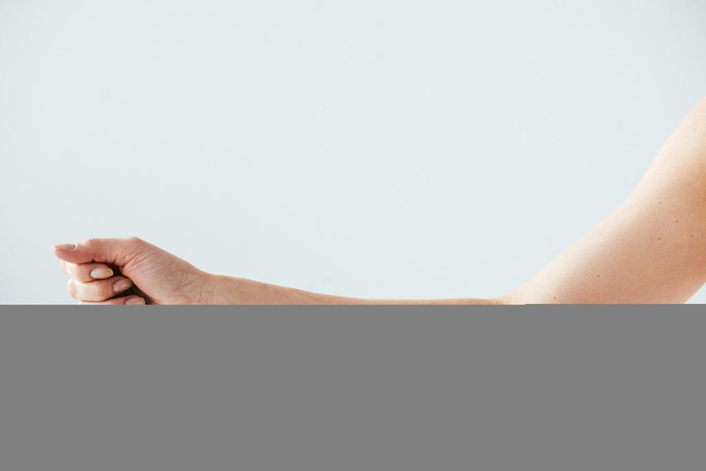 Ausgeschnittene Ansicht einer Frau, die mit dem Finger auf Maulwurf auf Weiß zeigt  - Foto, Bild