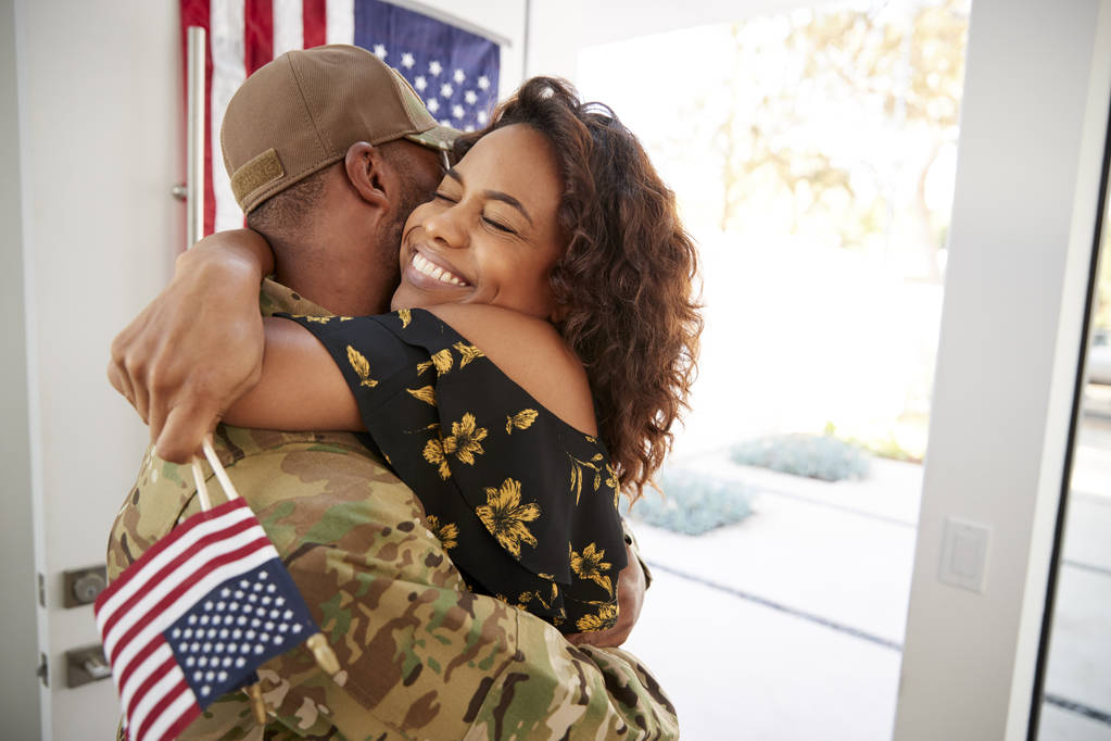 Χιλιάρα μαύρος στρατιώτης αγκαλιάζει τη γυναίκα του μετά την άφιξη πίσω στο σπίτι - Φωτογραφία, εικόνα