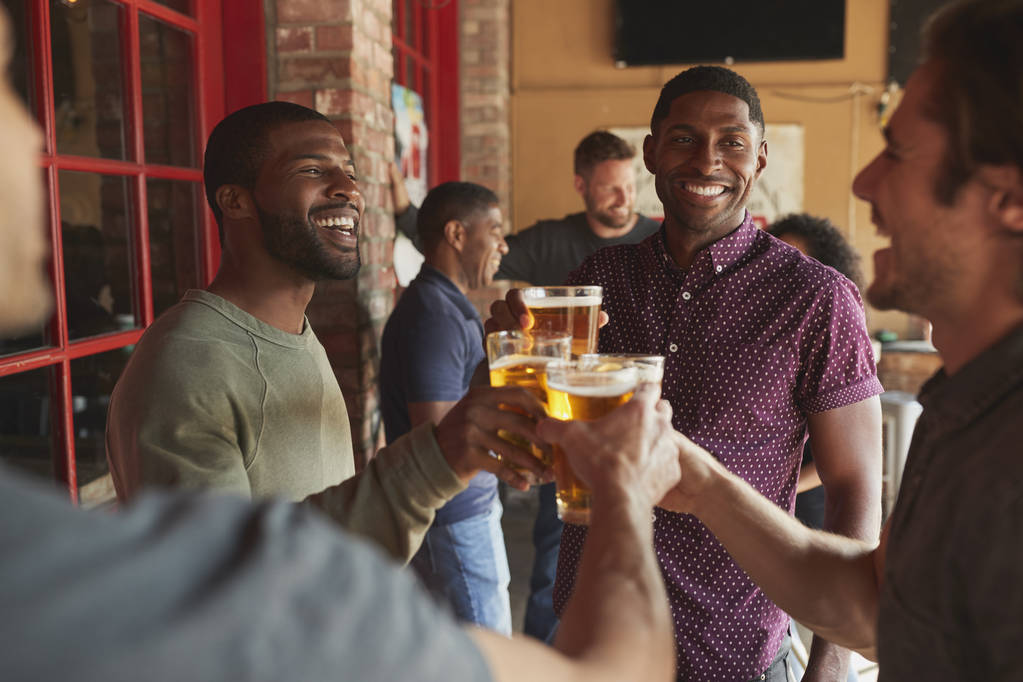 Skupina mužských přátel schůzka ve sportovním baru vytvoření přípitku dohromady - Fotografie, Obrázek