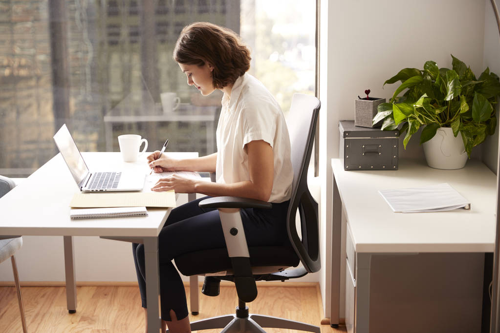 Mujer de negocios sentada en el escritorio trabajando en el ordenador portátil en la oficina moderna
 - Foto, Imagen