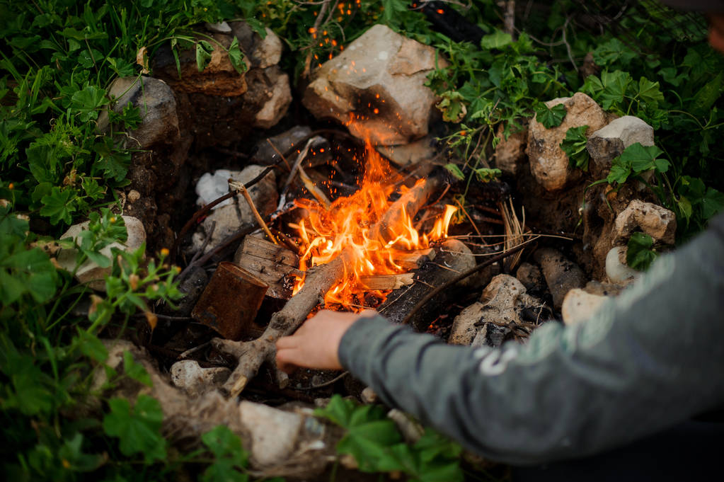 El hombre enciende fuego en un campamento turístico
 - Foto, Imagen