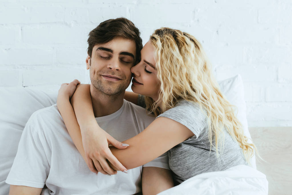 attractive blonde girlfriend hugging happy boyfriend with closed eyes - Photo, Image