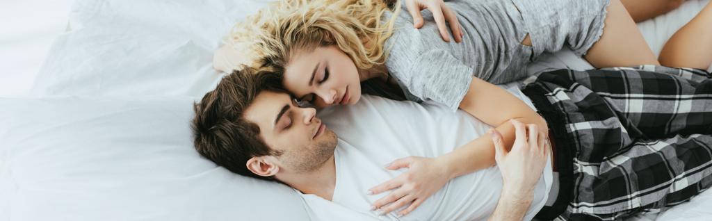 Панорамный снимок счастливой пары, обнимающейся на кровати
  - Фото, изображение