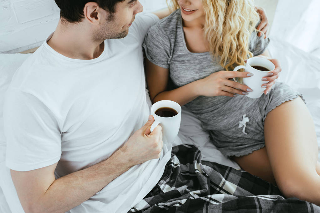 cropped view of man and blonde woman holding cups of coffee  - Photo, Image
