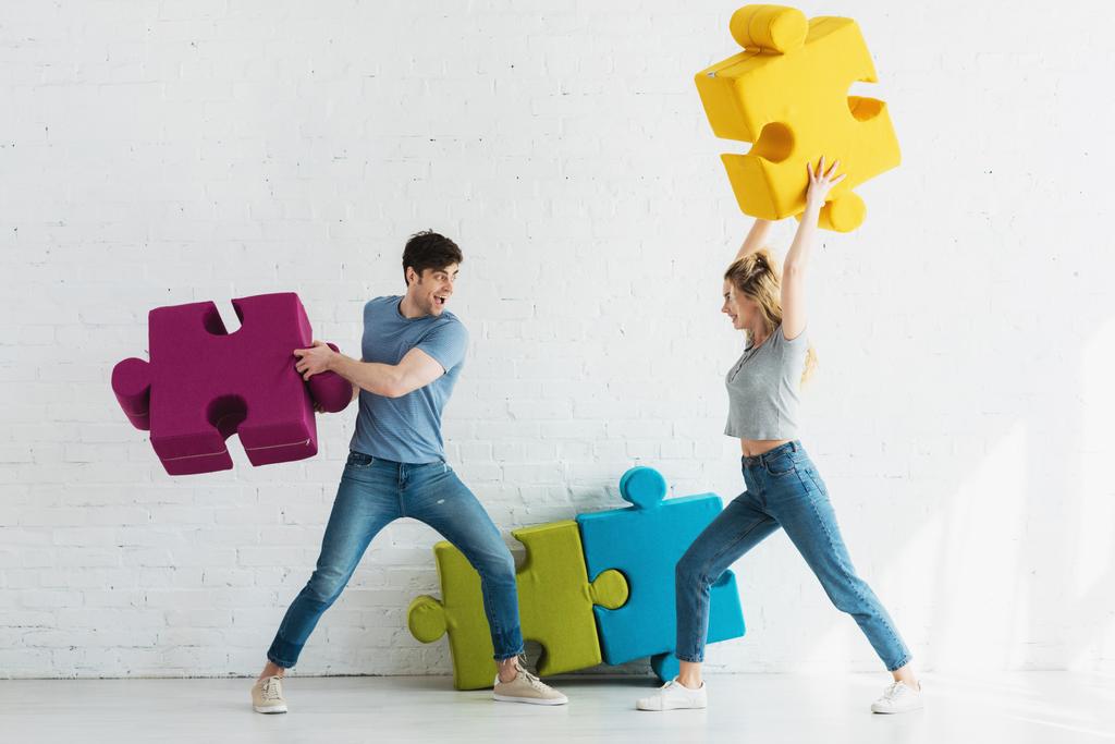 femme gaie et homme heureux se battant avec des pièces de puzzle à la maison
 - Photo, image