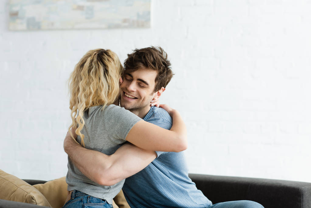 hombre feliz sonriendo mientras abraza chica rubia en casa
  - Foto, imagen