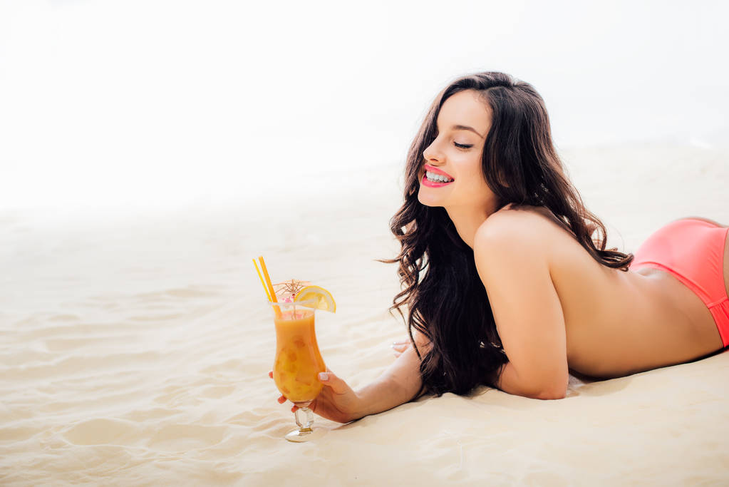 beautiful smiling topless girl with cocktail lying on beach with copy space - Photo, Image