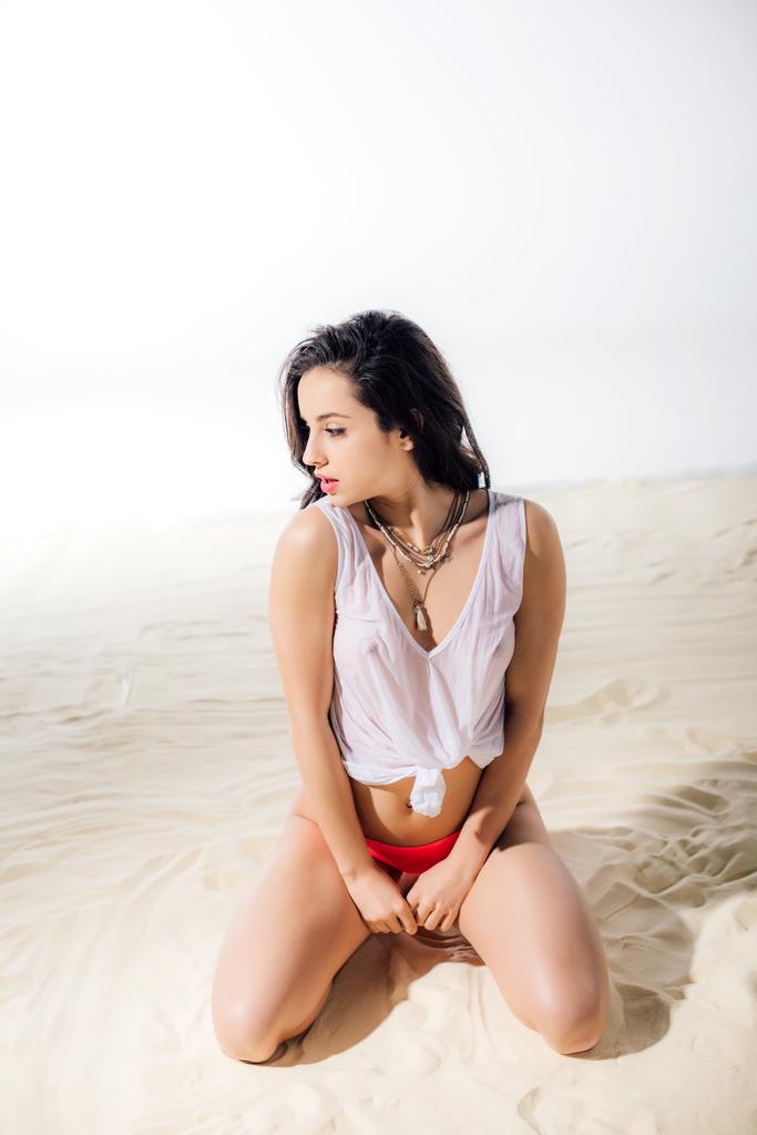 hermosa sexy chica en húmedo top sentado y posando en la playa
 - Foto, Imagen