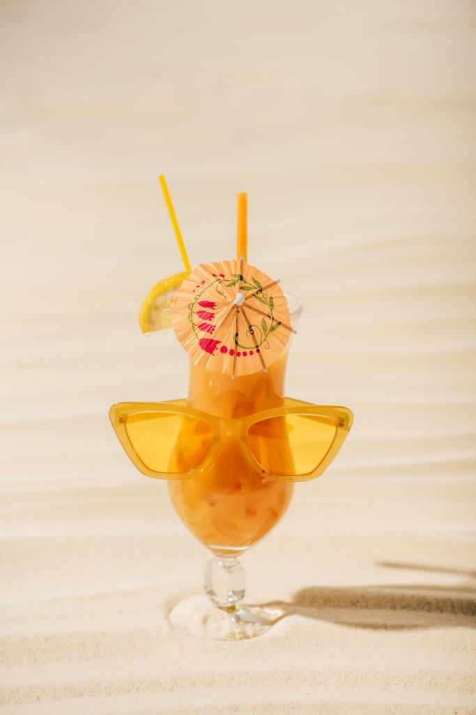 cocktail laranja com óculos de sol e guarda-chuva na praia de areia
 - Foto, Imagem