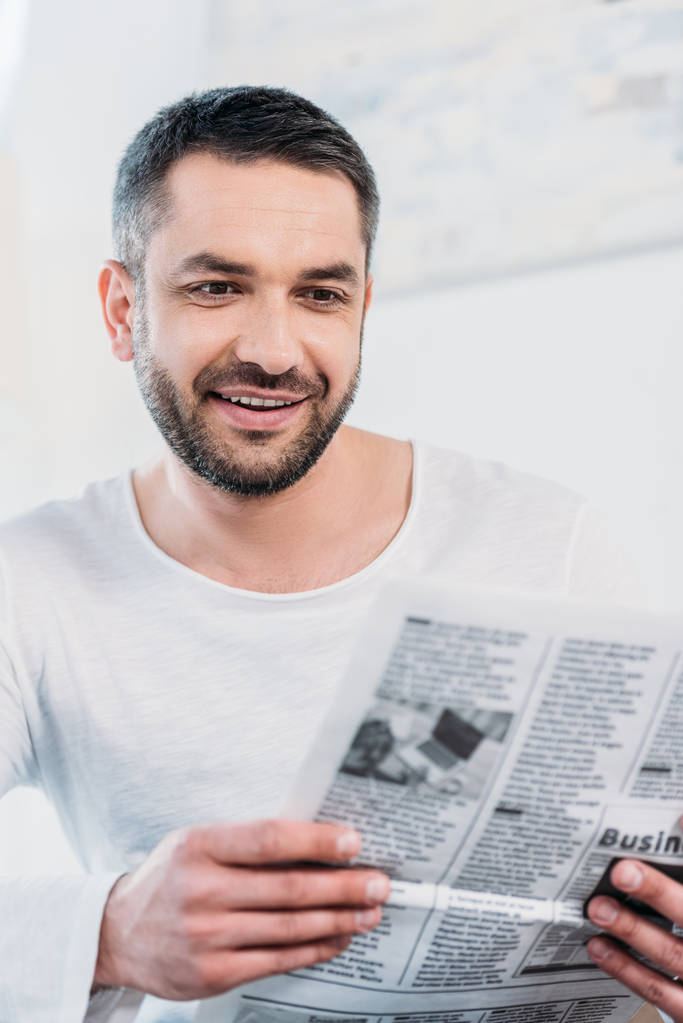 enfoque selectivo de hombre sonriente guapo leyendo el periódico en casa
 - Foto, imagen