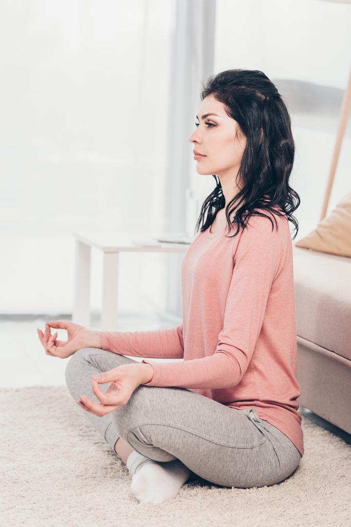 beautiful woman in Lotus Pose practicing meditation at home in Living Room - Photo, Image