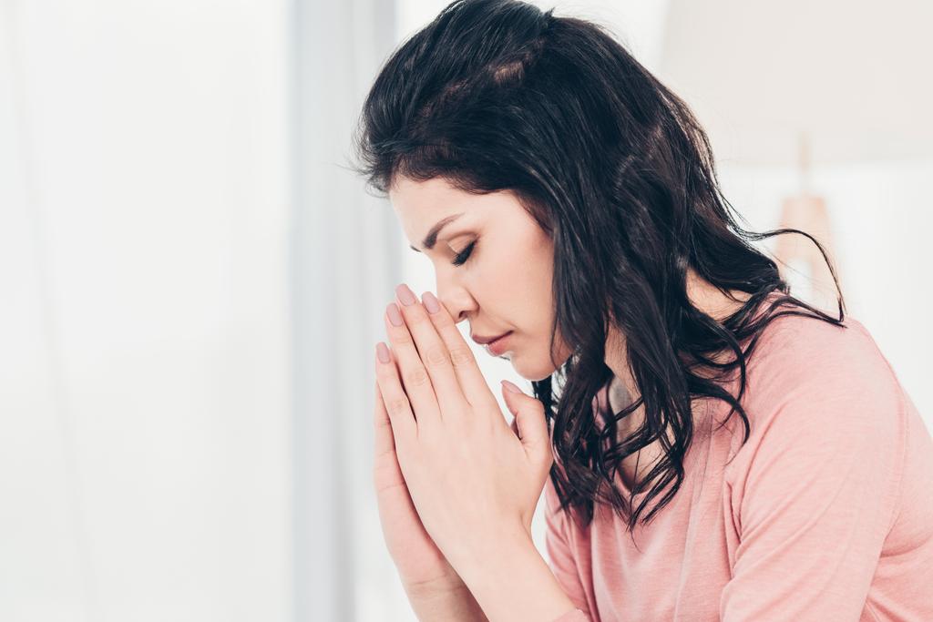 bela mulher com os olhos fechados fazendo por favor gesto e orando em casa com espaço de cópia
 - Foto, Imagem