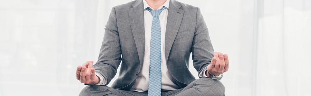 ロータスポーズで瞑想スーツを着たビジネスマンのパノラマショット  - 写真・画像