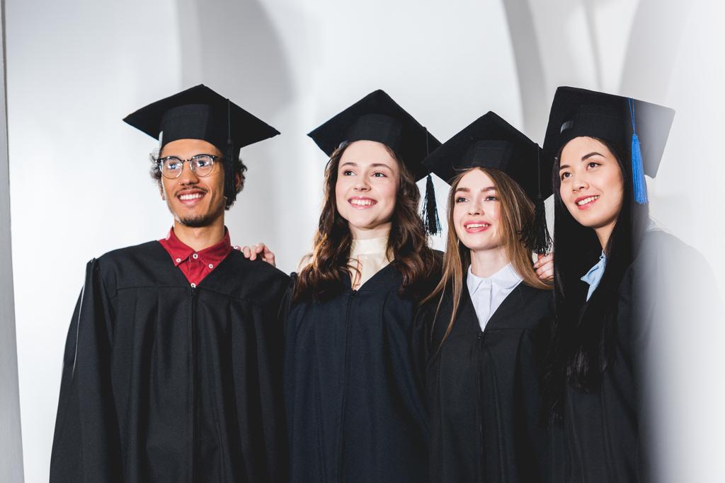 ομάδα των χαρούμενα φοιτητές σε καπέλα αποφοίτησης χαμογελώντας στο Πανεπιστήμιο  - Φωτογραφία, εικόνα