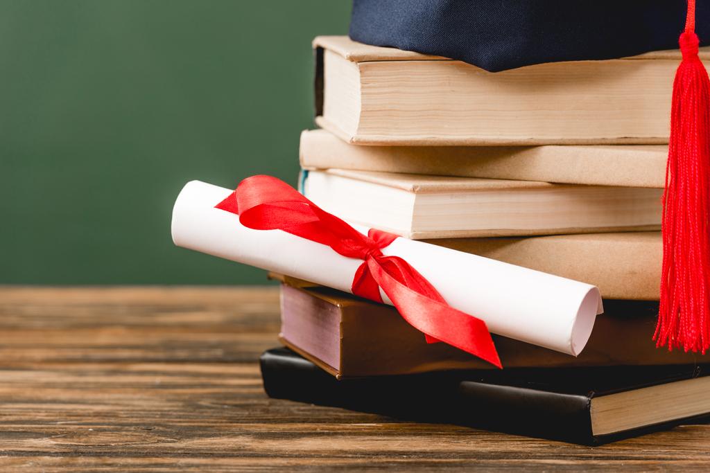 libri, tappo accademico e diploma su superficie in legno isolata su verde
 - Foto, immagini