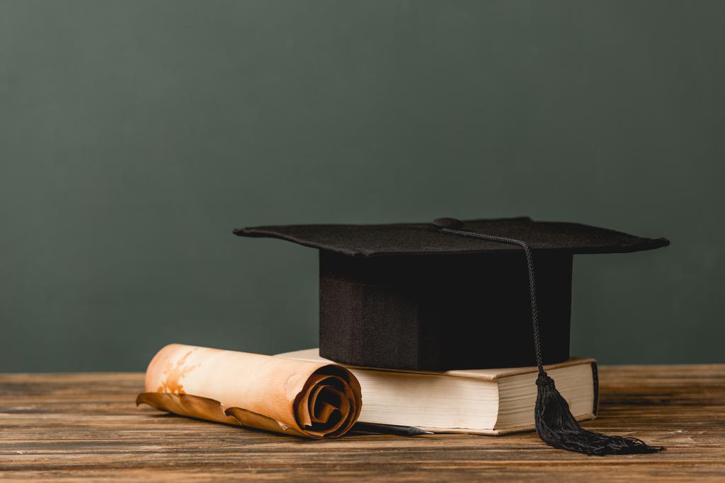 book, academic cap and scroll on wooden surface isolated on grey - Photo, Image