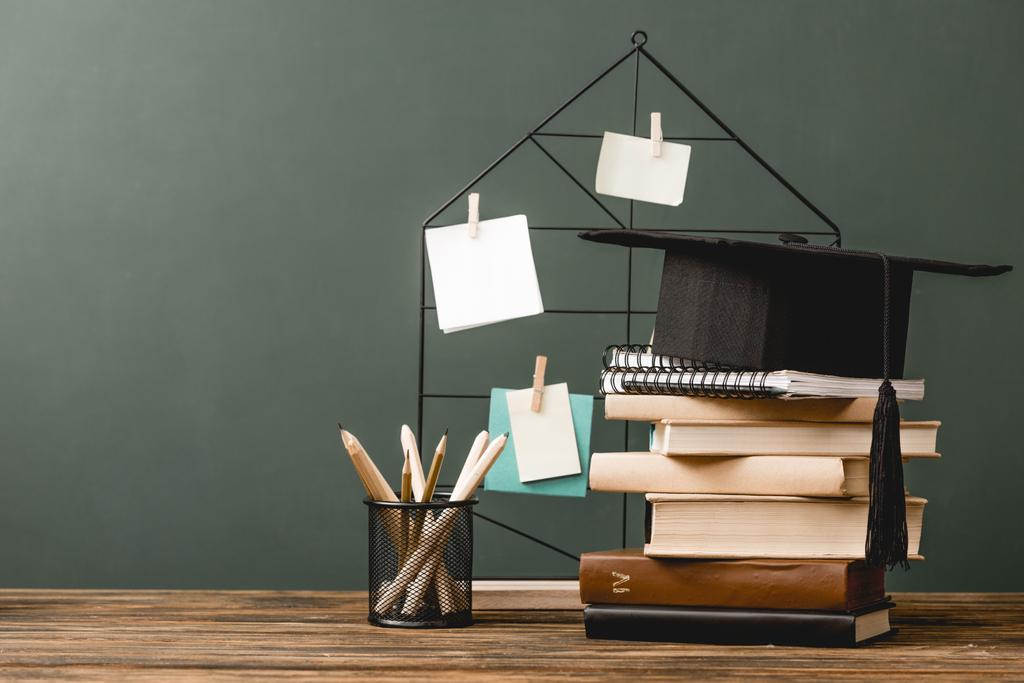 livres, cahiers, casquette académique, crayons et pinboard sur une surface en bois isolée sur gris
 - Photo, image