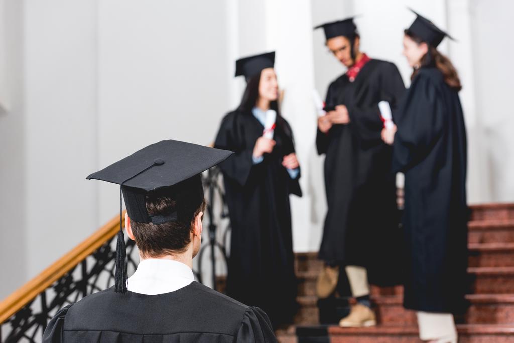 Rückansicht eines Studenten mit Abschlussmütze, der an der Universität steht  - Foto, Bild