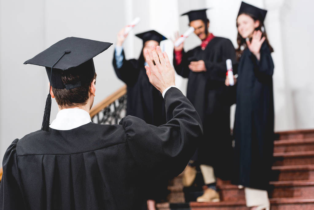 selectieve focus van student in Graduation Cap zwaaiende hand  - Foto, afbeelding