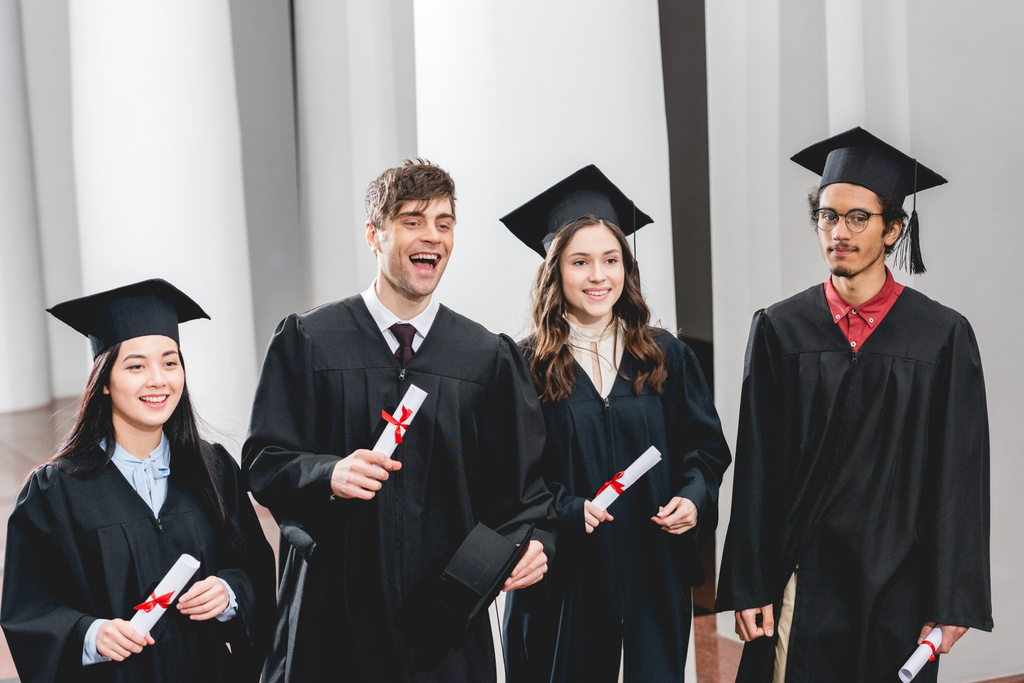 grupo sonriente en los estudiantes en vestidos de graduación con diplomas
  - Foto, imagen