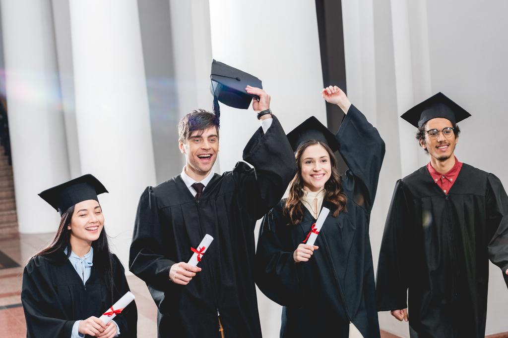 fröhliche Gruppe über Studenten, die gestikulieren und ihren Abschluss feiern, während sie Diplome halten  - Foto, Bild