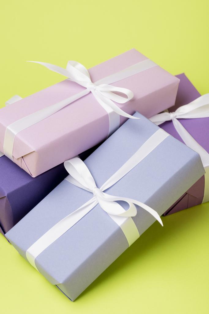 purple gift boxes with white ribbons on yellow surface - Photo, Image