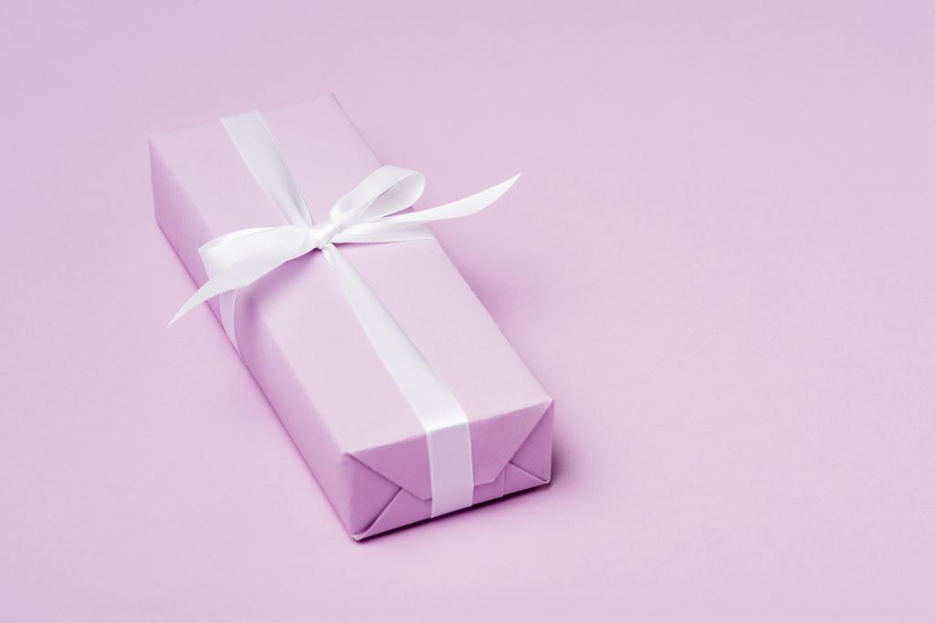 Geschenkbox mit weißem Band auf lila Oberfläche - Foto, Bild