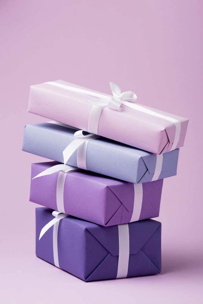 барвисті подарункові коробки з білими стрічками на фіолетовій поверхні
 - Фото, зображення