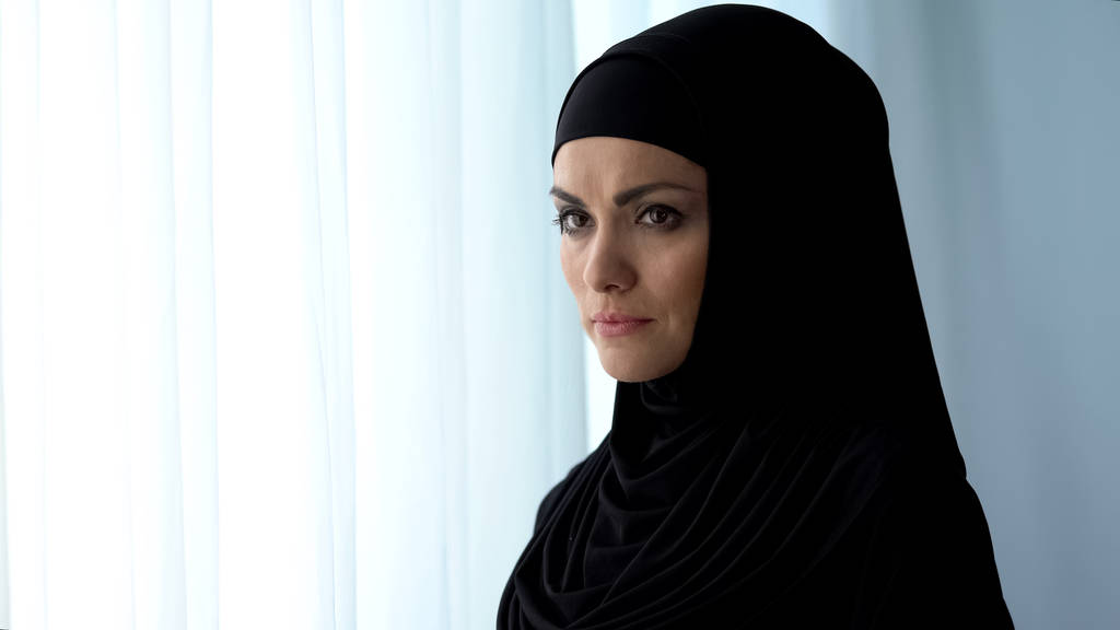 Яскрава арабська жінка, що стоїть біля вікна, відчуває біль, розчарування
 - Фото, зображення