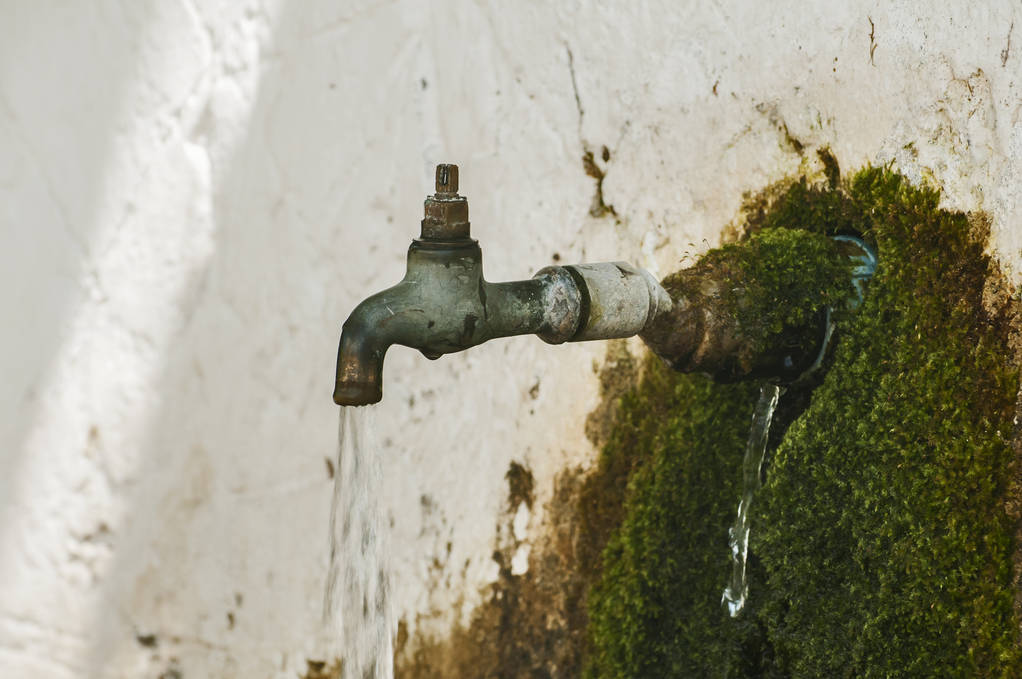 Robinet d'eau courante vétuste du robinet du robinet du vieux rural envahi par la mousse coulant de la fontaine
 - Photo, image