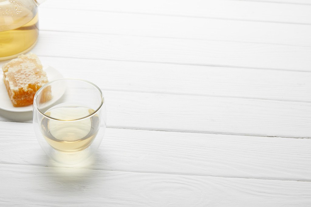 átlátszó üveg gyógynövényes tea és méhsejt fehér fából készült asztal, másolási tér - Fotó, kép